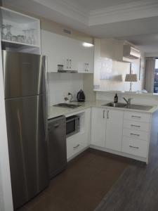 a kitchen with a stainless steel refrigerator and white cabinets at Lovely 2 Bedroom Serviced Apartment & Free Parking in Mandurah