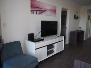 a living room with a tv and a chair at Lovely 2 Bedroom Serviced Apartment & Free Parking in Mandurah
