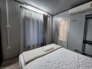 a bedroom with a white bed and a window at Srithanu Haus in Haad Chao Phao