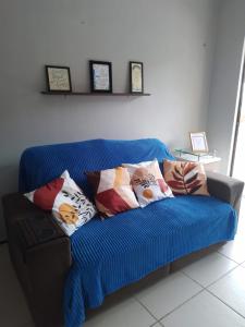 um sofá azul com almofadas num quarto em THE FOUNTAINS 110 - Apartamento em lindo condomínio pé na areia da Praia das Fontes em Beberibe - CE em Beberibe