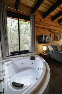 een groot wit bad in een kamer met ramen bij Cabaña Citrus para parejas in Mazamitla
