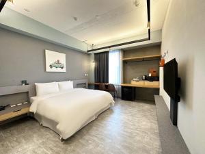 a bedroom with a large white bed and a desk at Thinker Hotel in Yingge