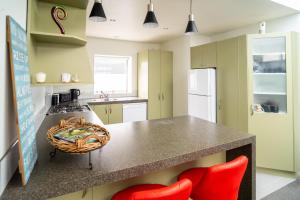 a kitchen with a counter and two red chairs at Hidden Gem in Rotorua