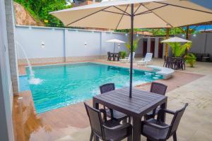 a table with an umbrella next to a swimming pool at ENJLU INN Selva Central in San Ramón