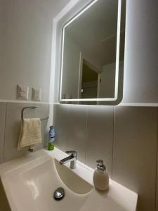 La salle de bains est pourvue d'un lavabo avec miroir et d'un distributeur de savon. dans l'établissement Getaway near Airport, à Guatemala