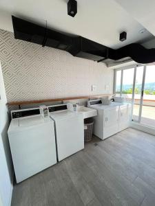 a kitchen with white appliances in a room with windows at Getaway near Airport in Guatemala