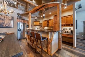 a kitchen with wooden cabinets and a bar with stools at Beautiful Mountain Modern Home 4Bedroom Spa in Whitefish