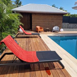 a wooden deck with chairs and a swimming pool at Villa MiLouMa in Saint-François