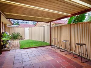 a patio with bar stools and a fence and grass at Benowa 1 Bedroom renovated townhouse in Gold Coast