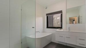 a white bathroom with a tub and a sink at Woodrun in Dinner Plain +15 photos
