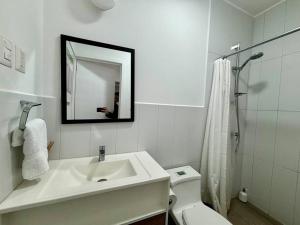 a bathroom with a sink and a toilet and a mirror at Rincon Moderno cerca aeropuerto in Guatemala