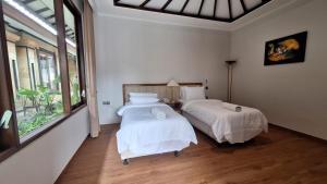 a bedroom with two beds and a large window at Rabasta Enjoy Kuta in Denpasar