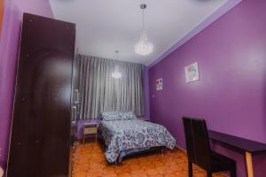Dormitorio púrpura con cama y escritorio en Casa - Huancayo - Zoológico Cerrito de la Libertad, en Huancayo