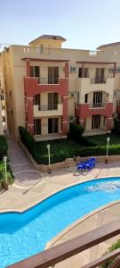 an apartment complex with a swimming pool in front of a building at For Family شاليه in Suez