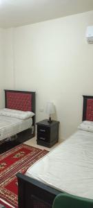 una camera con due letti e un tavolo con una lampada di For Family شاليه a Suez