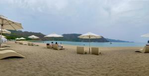 a beach with umbrellas and people sitting on the sand at Pico De Loro room Jacana A Bldg. in Nasugbu