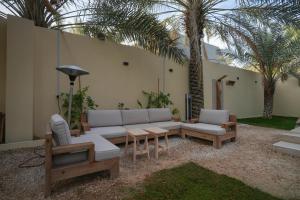un patio con sofá, sillas y palmeras en شاليه ايفالو, en Al Hofuf