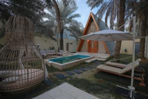 a house with a swimming pool with a hammock and an umbrella at شاليه ايفالو in Al Hofuf