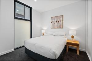 メルボルンにあるModern Apartment on Burgundy precinct & Parklandsのベッドと窓のある白い寝室
