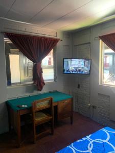 1 dormitorio con escritorio, TV y cama en hotel Las Cabañitas 8873-3748 en Managua