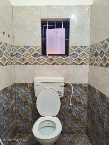 a bathroom with a toilet and a window at Pagis place in Canacona