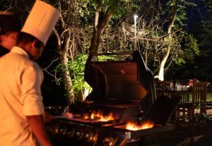 a man in a chefs hat standing next to a grill at Lario Resort Sigiriya in Sigiriya