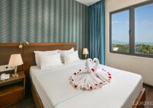 un dormitorio con una cama con una decoración de cisne en L'emore Hotel Da Nang en Da Nang
