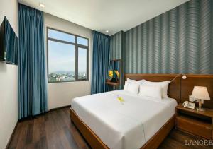 a bedroom with a large white bed and a window at L'emore Hotel Da Nang in Danang