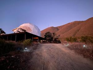 a building with a glass dome next to a dirt road at Domo en los vilos, parcela cascabeles in Los Vilos