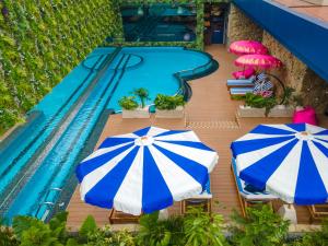 雅加達的住宿－Ashley Tugu Tani Menteng，两把蓝白遮阳伞,毗邻一个游泳池