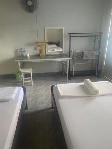 um quarto com duas camas, uma mesa e um espelho em Albatross Guesthouse @ Thungwualaen Beach em Pathiu