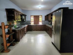 een keuken met houten kasten en een roestvrijstalen koelkast bij Villa Guitarra in San Jerónimo