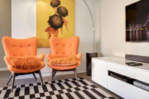 2 orangefarbene Stühle in einem Wohnzimmer mit einem TV in der Unterkunft Cosy 1-Bedroom Apartment Close to the City in Sydney