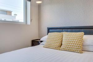 ein Bett mit gelber und weißer Bettwäsche und einem Fenster in der Unterkunft Cosy 1-Bedroom Apartment Close to the City in Sydney