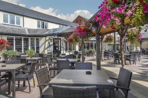 un patio al aire libre con mesas, sillas y flores en The Three Swans Hotel, Market Harborough, Leicestershire, en Market Harborough