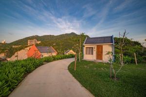 a path leading to a house with a mountain in the background at Life Club Beach Resort in Quy Nhon