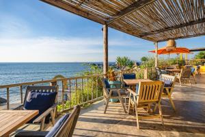 a deck with chairs and tables and the ocean at Life Club Beach Resort in Quy Nhon