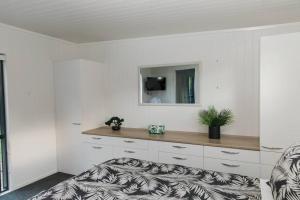 a white room with a desk with a mirror at Bombay Hills Modern Retreat in Auckland