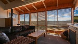 a living room with leather couches and a large window at Fountains 6 in Mount Hotham
