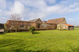 an old stone building with a grass yard at Long Shed Cottage in Thirsk