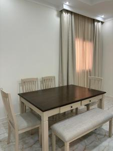 mesa de comedor con sillas blancas y mesa de madera en MFAPARTMENT, en Al Budayyiâ€˜