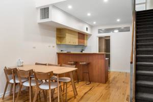 a kitchen and dining room with a wooden table and chairs at Lego-Aerospace Free Parking CBD Chinatown in Adelaide +28 photos
