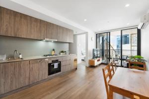 a kitchen with wooden cabinets and a dining room with a table at City Escape Realm 1 BR Apt Wi-Fi Pool Gym SPA in Adelaide