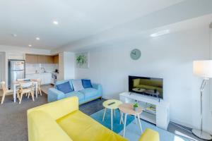a living room with a yellow couch and a kitchen at Walk to Central Market Parking GYM&POOL City View in Adelaide