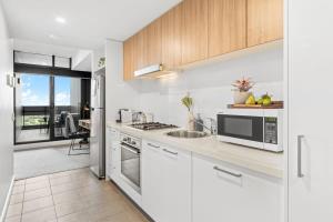 een witte keuken met een wastafel en een magnetron bij Comfy place with fabulous view Penthouse level in Adelaide
