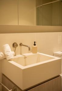 a white sink in a bathroom with a mirror at Pure Luxury Modern Apt Heart of CBD Car Park in Adelaide