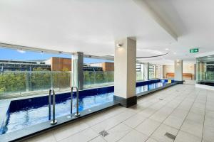 a large swimming pool in a building with windows at CBD Modern 2BR Free Parking in Adelaide