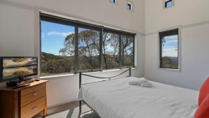 a bedroom with a bed and two large windows at Karoondah 7 in Mount Hotham