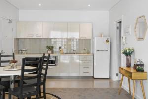 eine Küche mit einem Tisch und einem weißen Kühlschrank in der Unterkunft 1BR Adelaide CBD Apt The Best Location in Adelaide