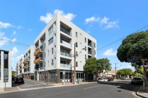 ein weißes Apartmenthaus auf einer Straße mit parkenden Autos in der Unterkunft 1BR Adelaide CBD Apt The Best Location in Adelaide
